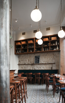 Salle restaurant Le Comptoir de la Gastronomie Paris Ier — pierre de taille chaises bistrot globes suspendus étagères boiseries — rénovation Bilal Deshayes architecte d'intérieur Paris