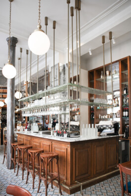 Bar central Le Comptoir de la Gastronomie Paris Ier — comptoir marbre boiseries verres suspendus laiton carreaux ciment — rénovation Bilal Deshayes architecte d'intérieur Paris 