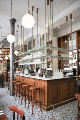Bar central Le Comptoir de la Gastronomie Paris Ier — comptoir marbre boiseries verres suspendus laiton carreaux ciment — rénovation Bilal Deshayes architecte d'intérieur Paris