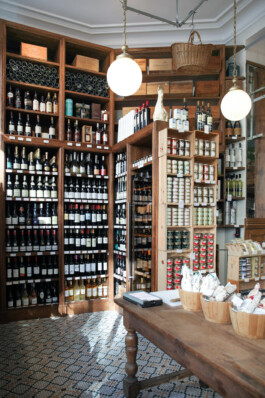 Cave à vins épicerie fine Le Comptoir de la Gastronomie Paris Ier — étagères boiseries vins conserves table en bois carreaux ciment — rénovation Bilal Deshayes architecte d'intérieur Paris