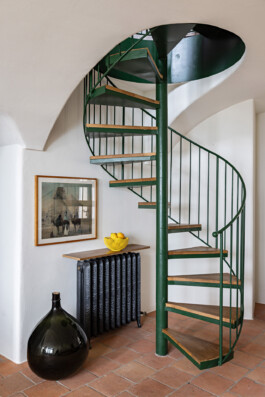 Escalier hélicoïdal en métal vert sous voûte avec sol terracotta et bonbonne en verre, maison Grimaldi Ligurie — Bilal Deshayes architecte d'intérieur