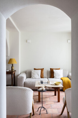 Salon lumineux avec tomettes, fauteuils bouclé et grande fenêtre donnant sur le village, Grimaldi Superiore — Bilal Deshayes architecte d'intérieur